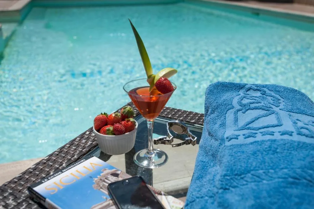 Cocktail e fragole su tavolino a bordo piscina con telo blu