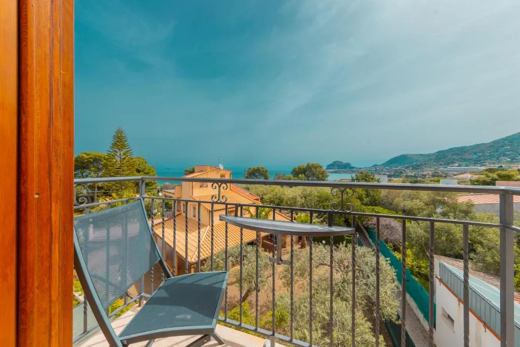 Balcone con sedia affacciato sul giardino e mare in lontananza