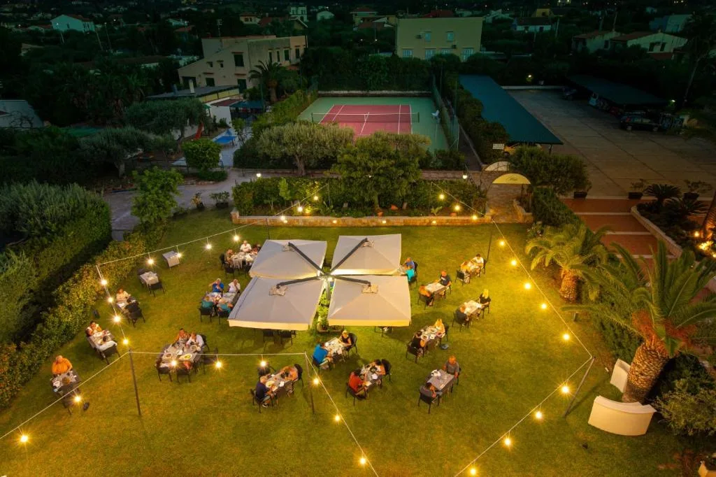 Veduta aerea della cena all'aperto in giardino con luci e campo da tennis