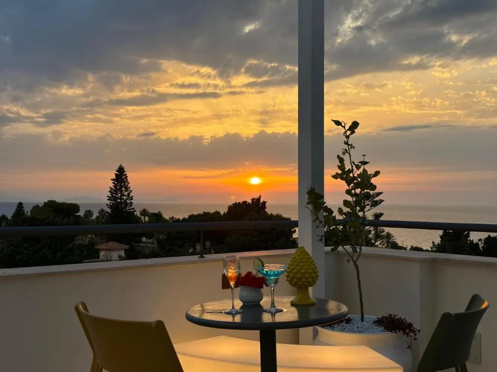 Tavolo sul balcone con cocktail e vista sul tramonto sul mare