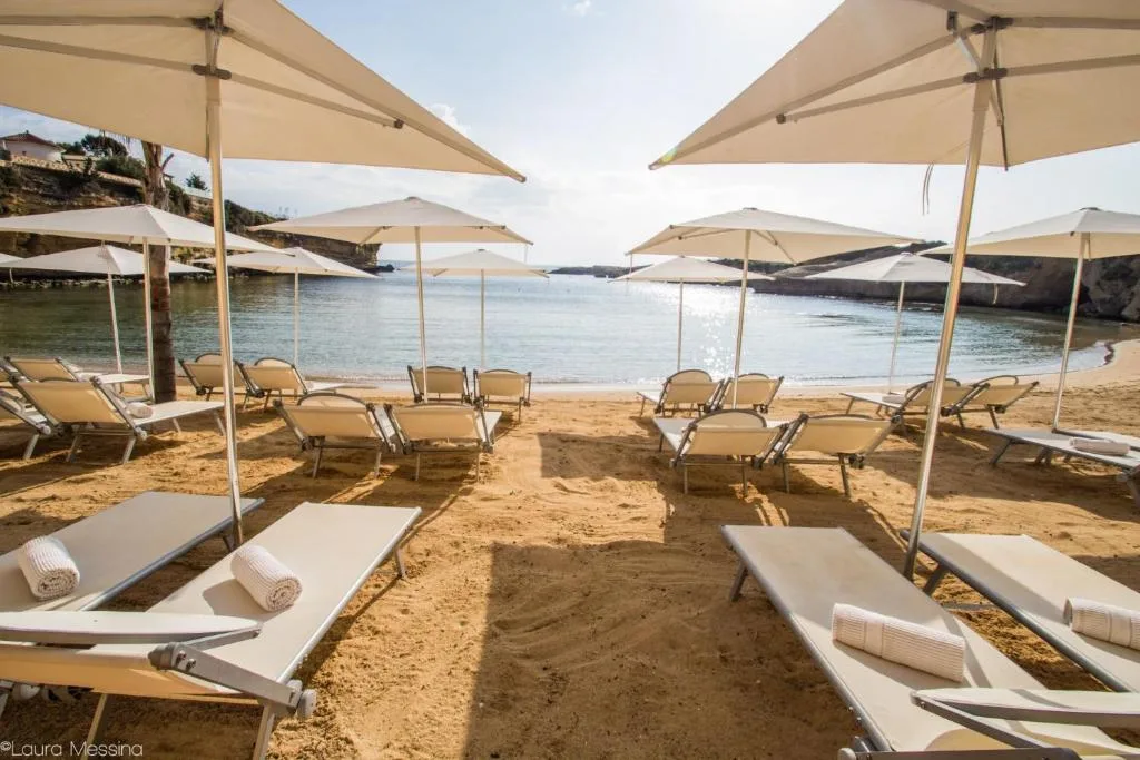 Lettini e ombrelloni bianchi sulla sabbia con vista sul mare al tramonto