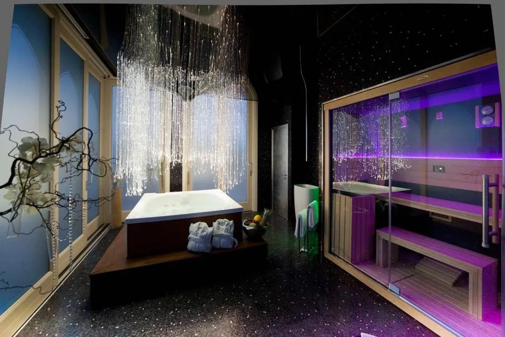 Bagno di lusso con vasca idromassaggio, sauna con luci viola e lampadario di cristalli