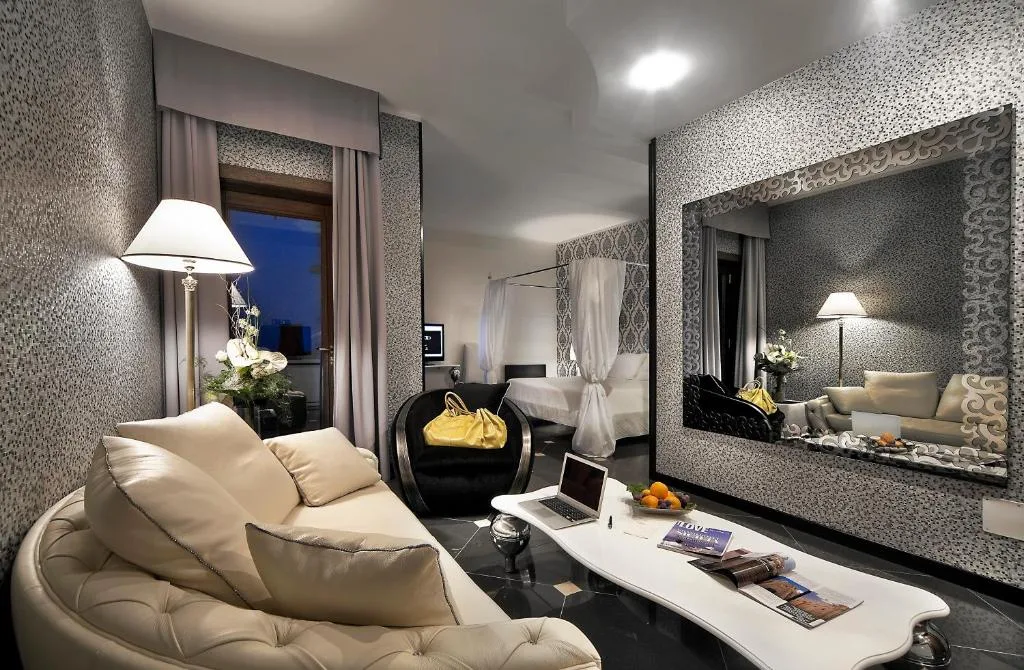 Suite elegante con divano in pelle, grande specchio e camera da letto sullo sfondo