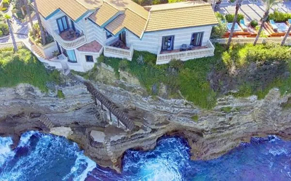 Ville sul bordo della scogliera con scala che scende verso il mare mosso