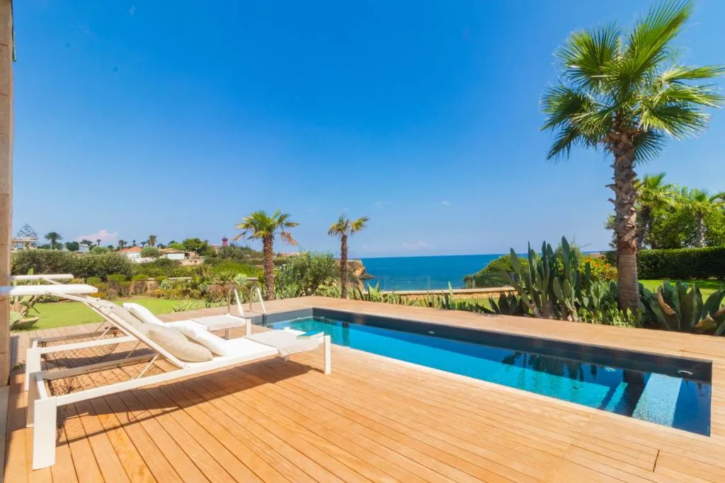 Piscina privata su terrazza in legno con lettino e palme vista mare
