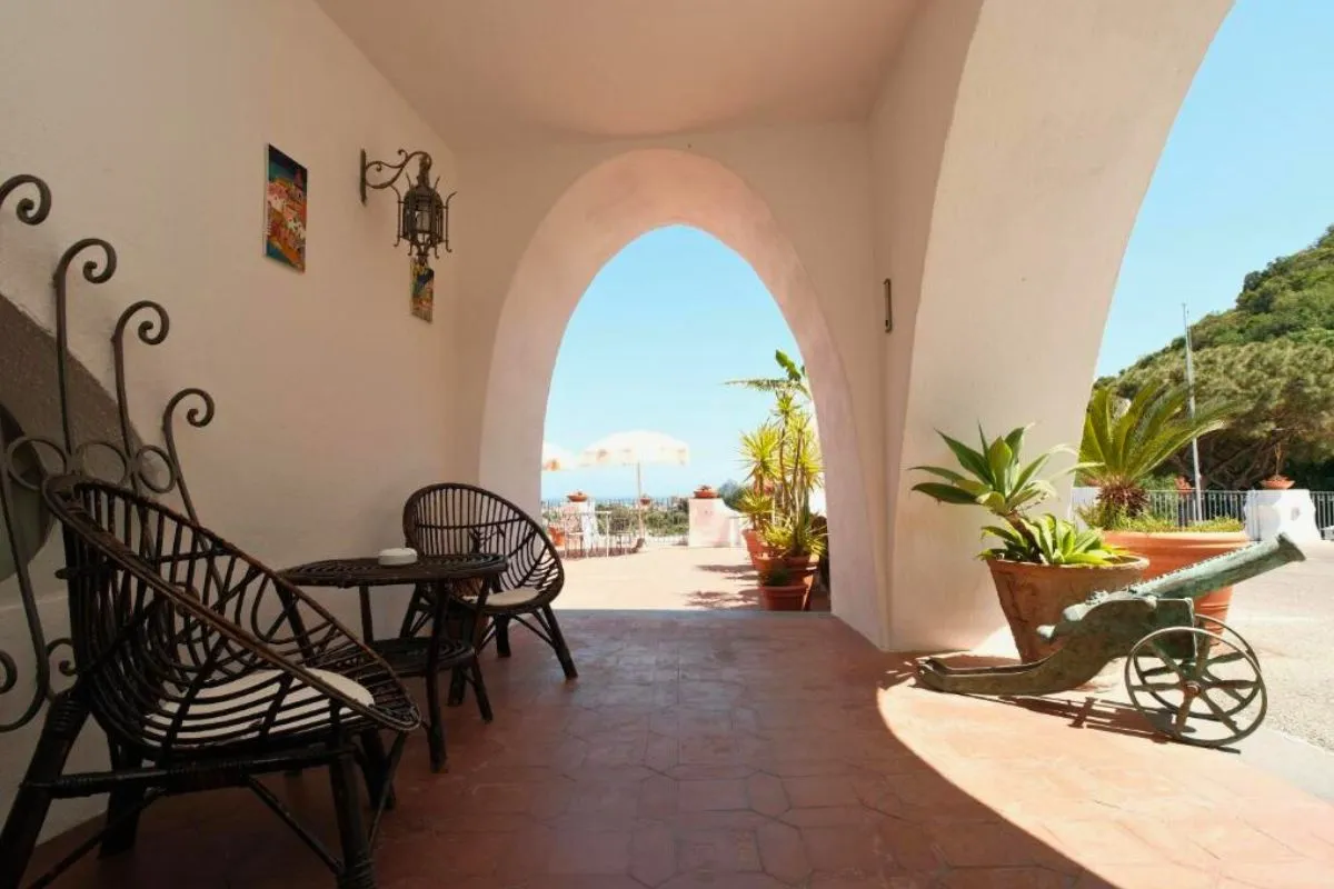 Angolo relax con poltrone in vimini sotto un arco bianco e vista sulla terrazza
