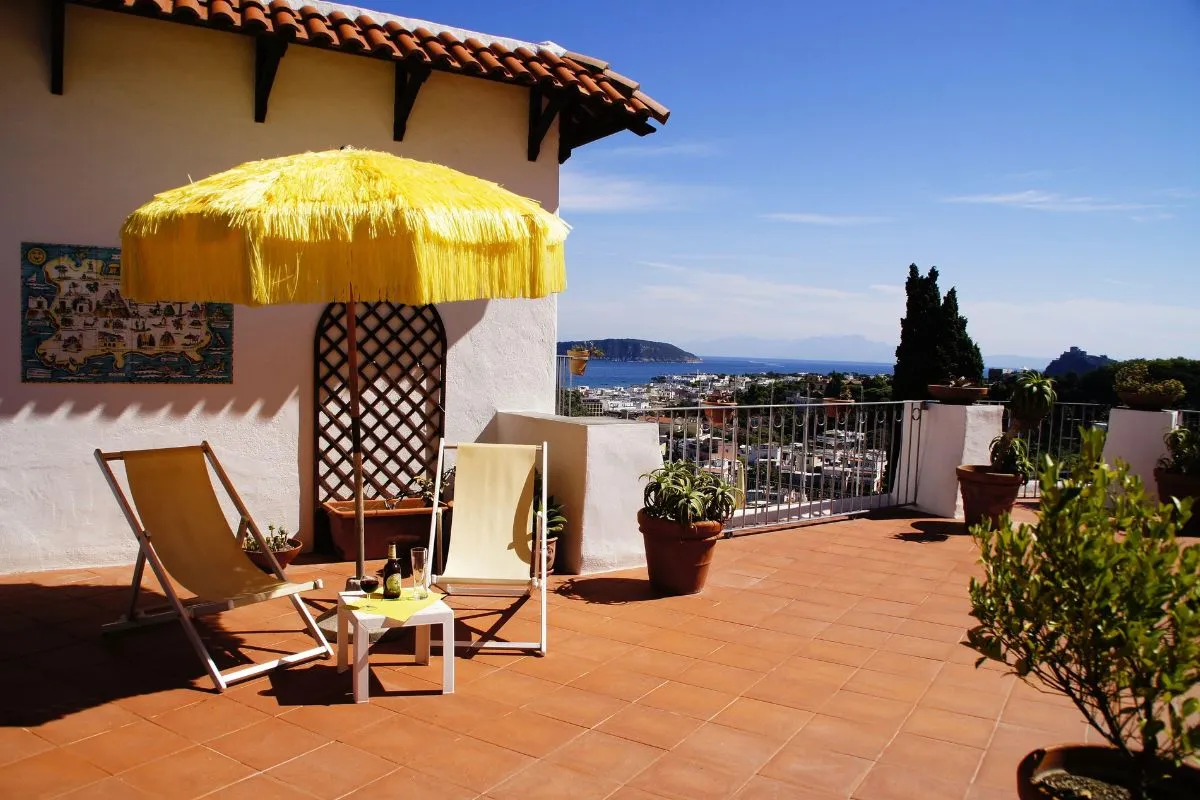 Terrazza privata con sdraio, ombrellone giallo in paglia e vista sul mare e sul golfo