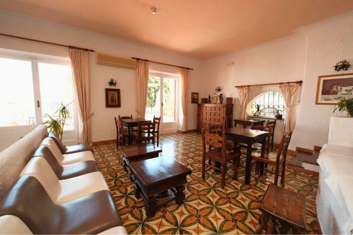 Sala soggiorno con divani in pelle, tavolini in legno e pavimento in maioliche decorate
