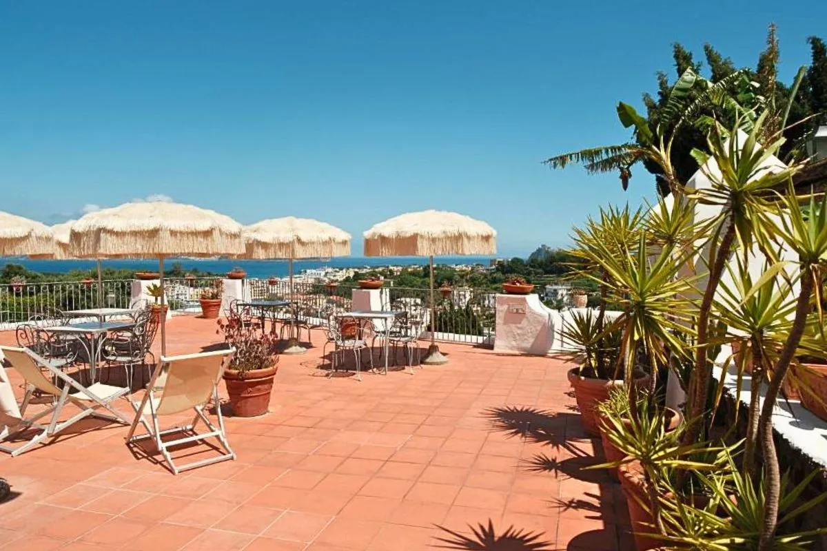 Terrazza panoramica con tavoli, sedie in ferro battuto, ombrelloni in paglia e vista sul mare