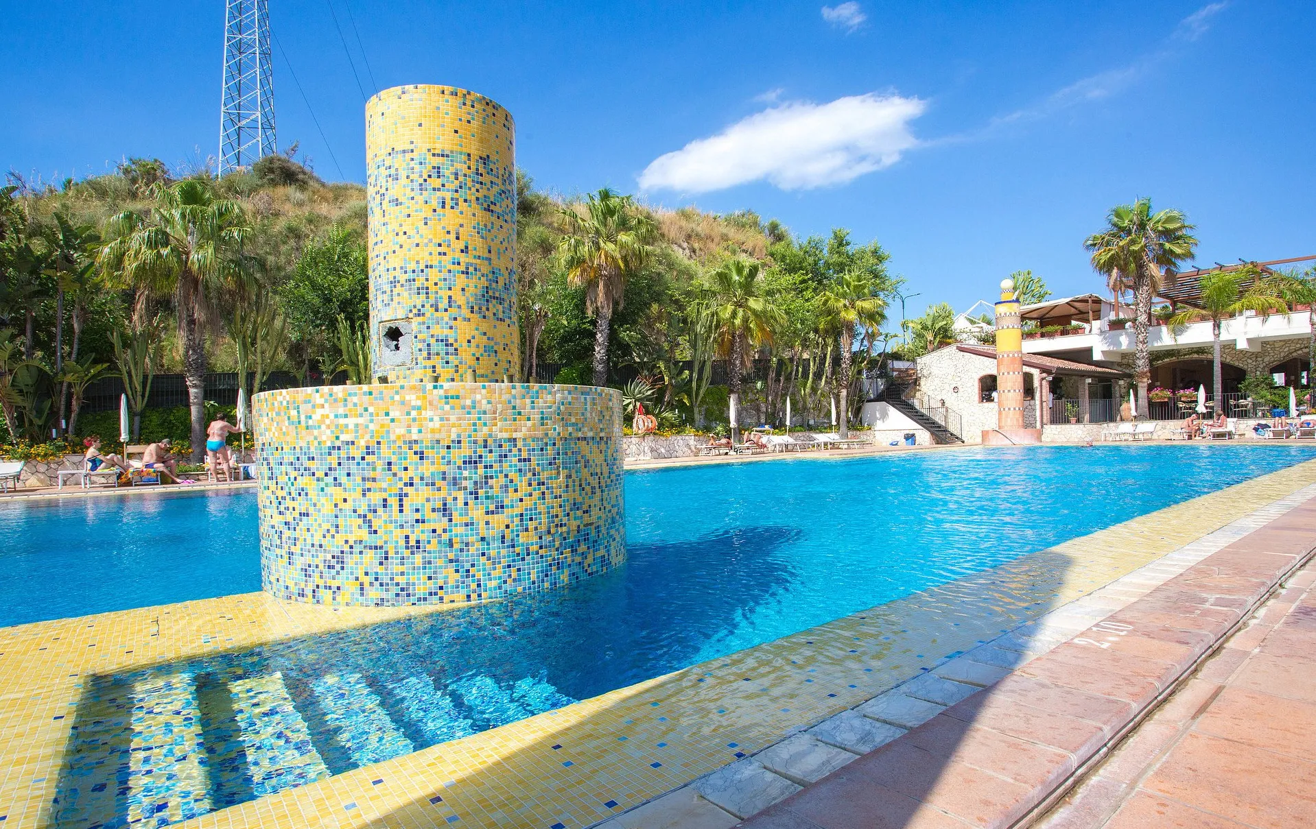 Dettaglio della piscina con colonna a mosaico colorato giallo e blu