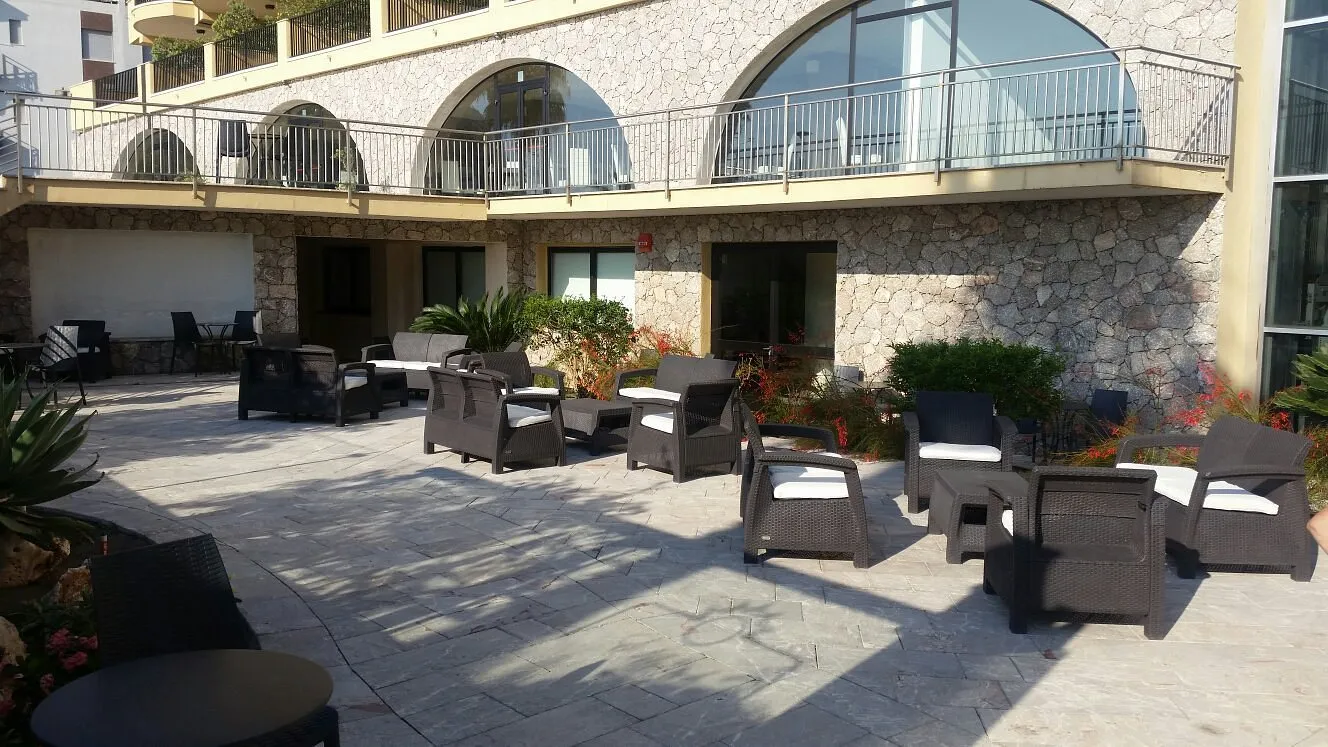 Terrazza esterna con poltrone in rattan e muro in pietra dell'hotel