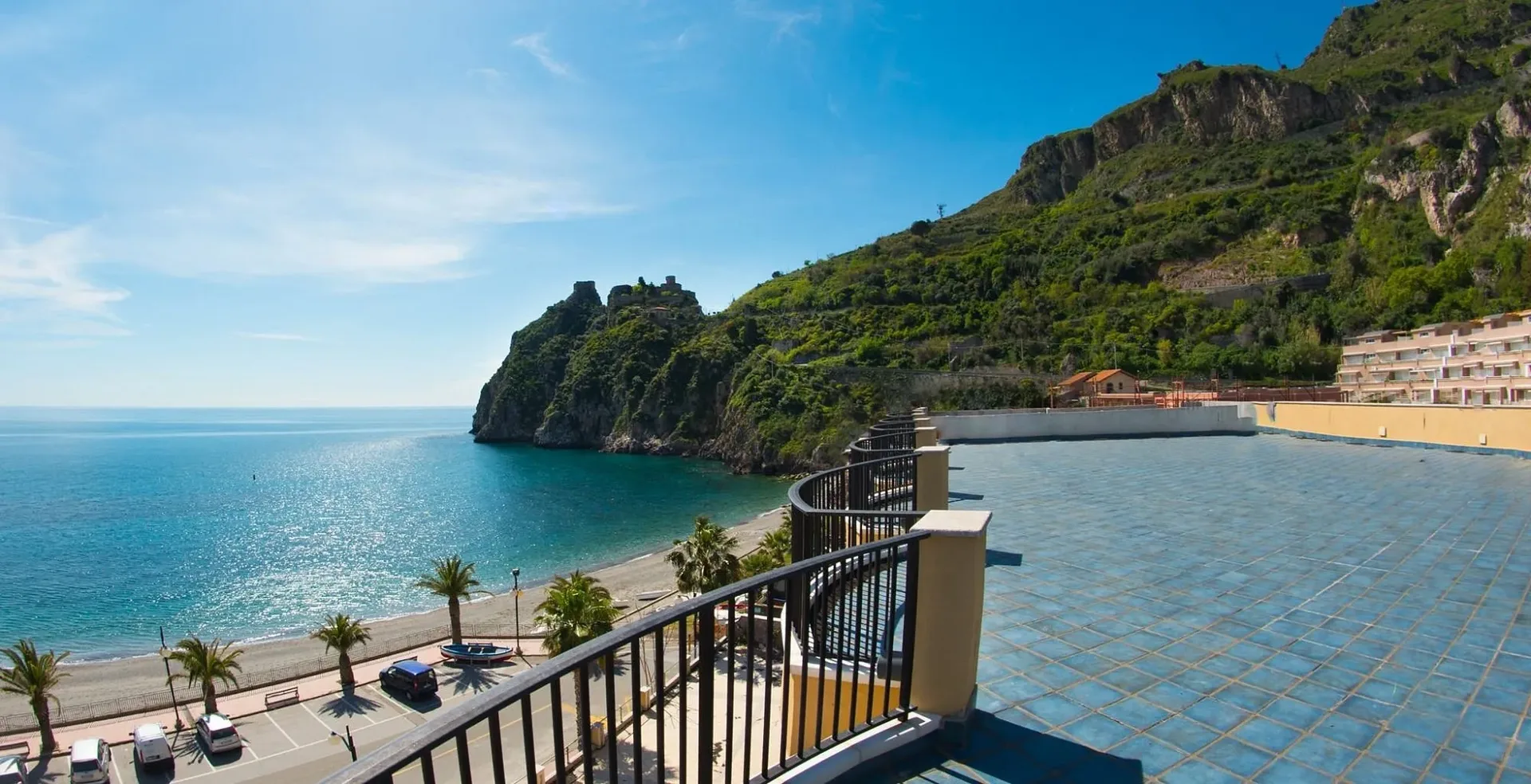 Vista panoramica dal balcone su mare, spiaggia e promontorio con castello