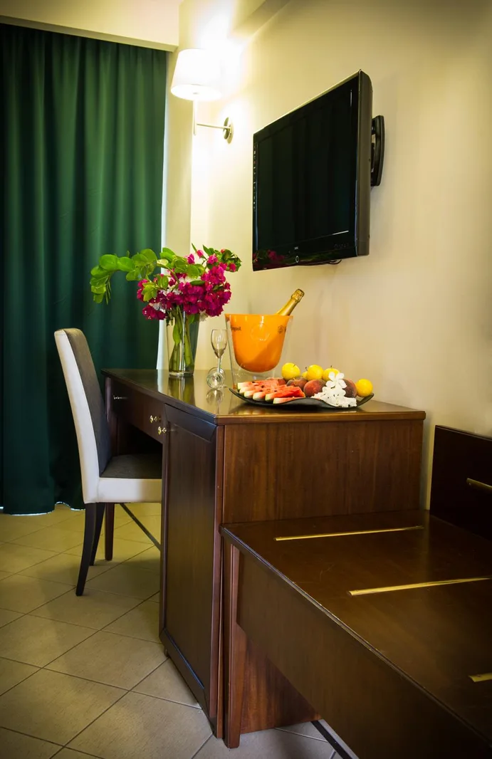 Scrivania in legno della camera con TV, fiori e piatto di frutta