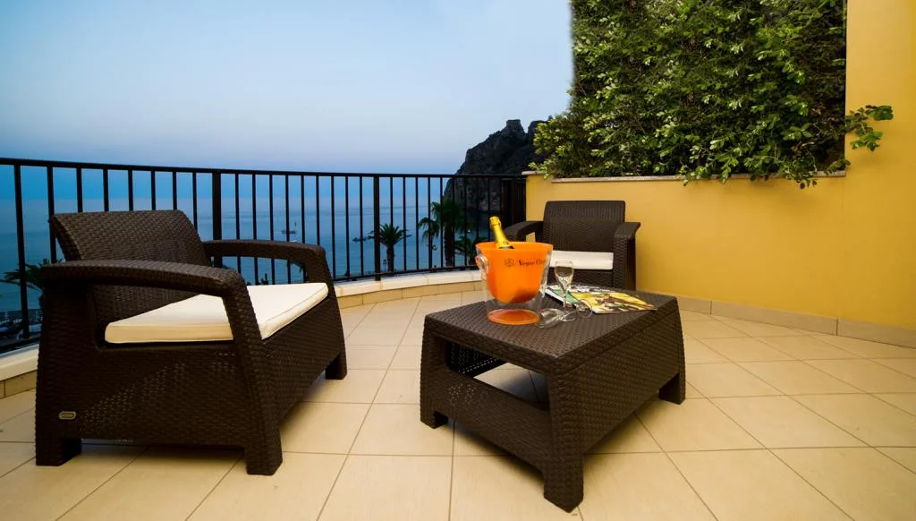 Terrazza con poltrone in rattan e champagne con vista sul mare al tramonto