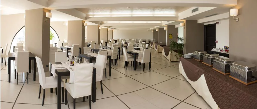 Ampia sala ristorante con tavoli apparecchiati e sedie bianche