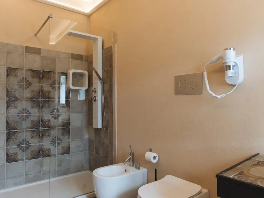 Bagno con doccia rivestita di piastrelle decorate, bidet e wc