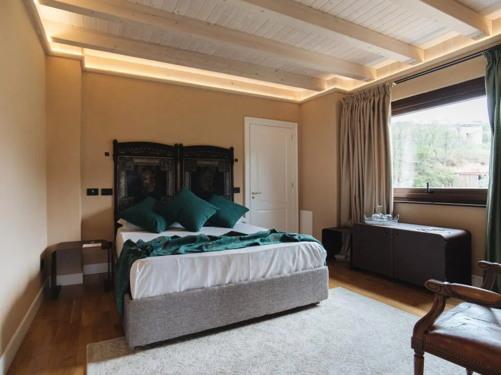 Camera da letto elegante con cuscini verdi, travi in legno e ampia finestra