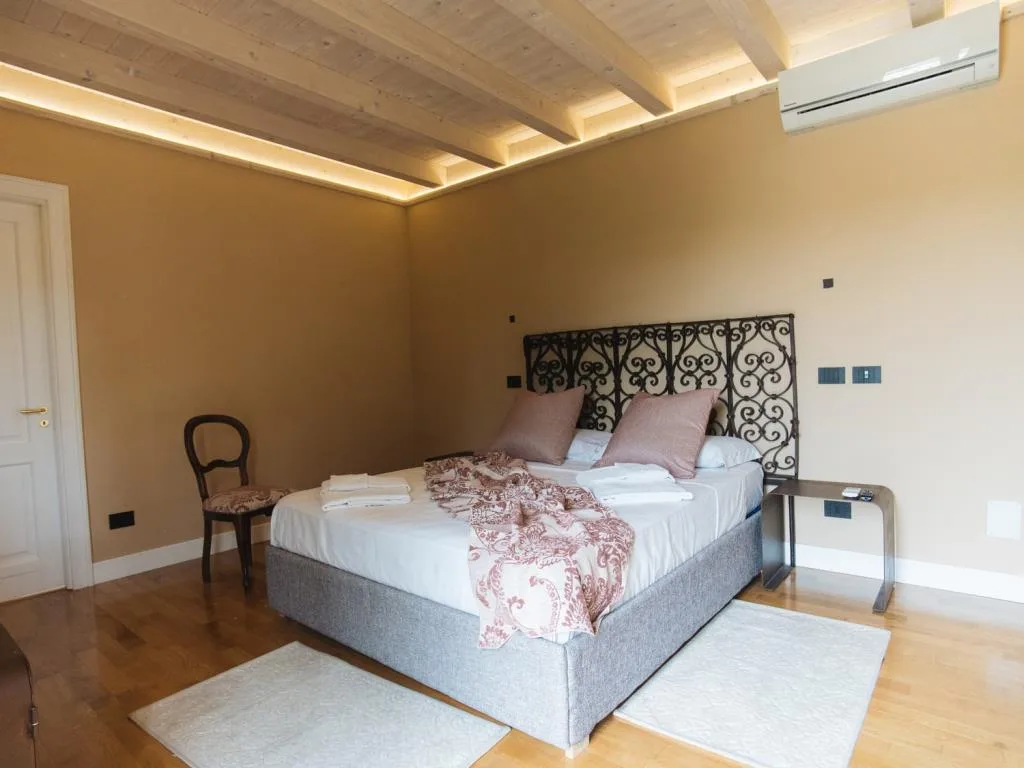 Camera da letto con soffitto in legno, letto matrimoniale e testiera in ferro battuto