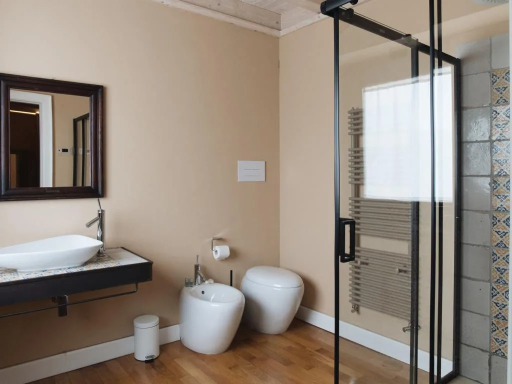 Bagno moderno con lavabo, bidet, wc e doccia con box in vetro e piastrelle decorate