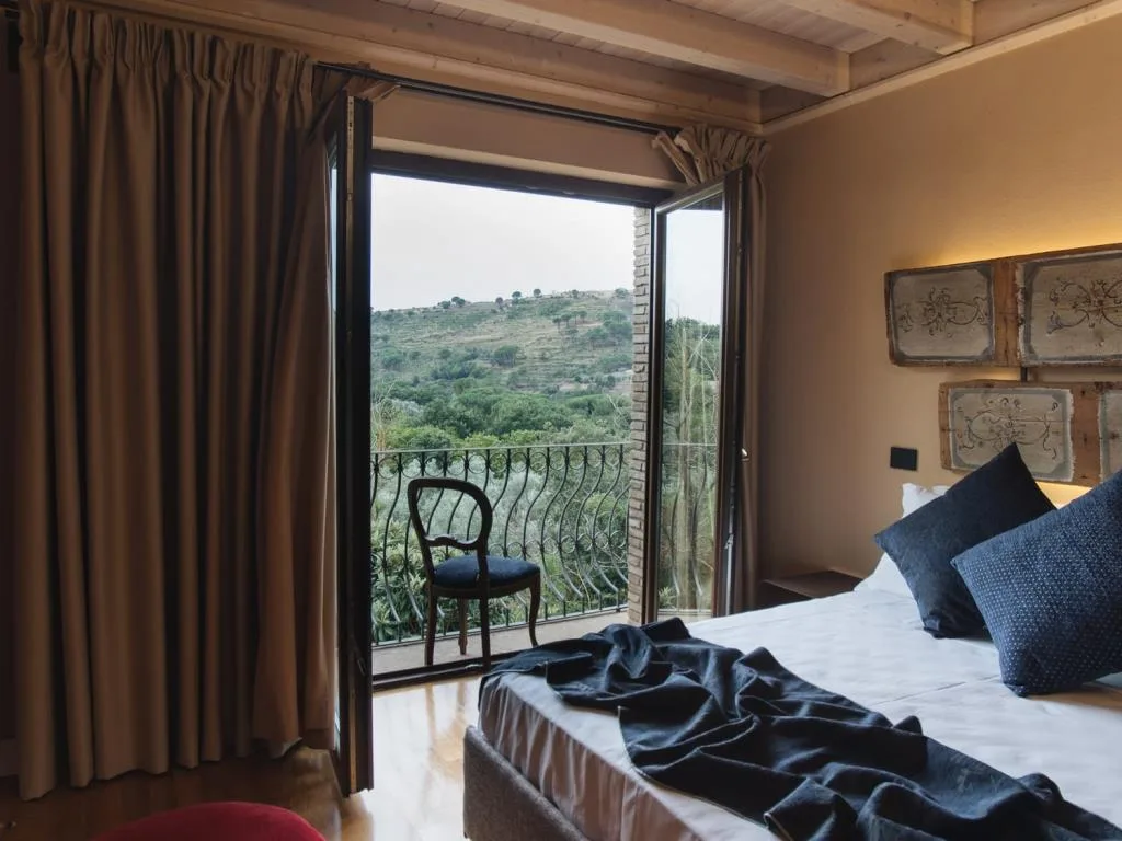 Camera con letto e portafinestra affacciata su balcone con vista sulle colline