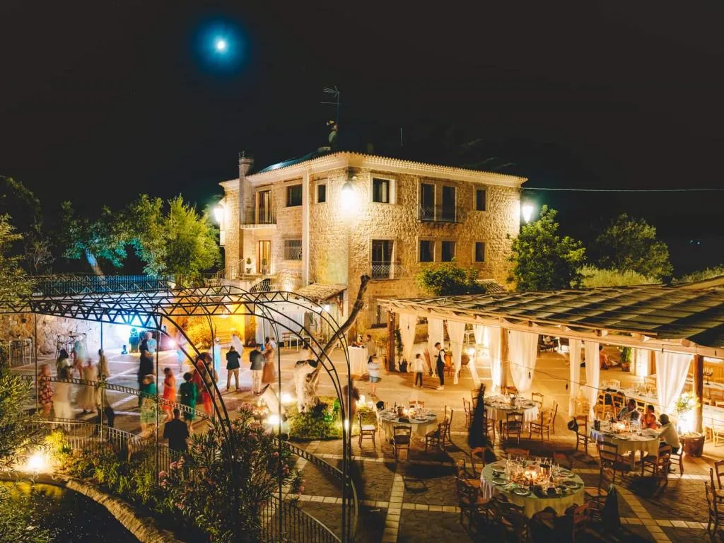 Struttura in pietra illuminata di notte con evento all'aperto sotto la luna