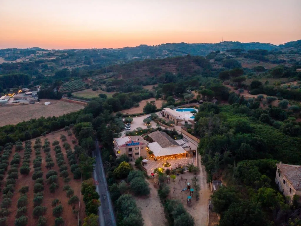 Veduta aerea della struttura in campagna con piscina, uliveti e colline al tramonto