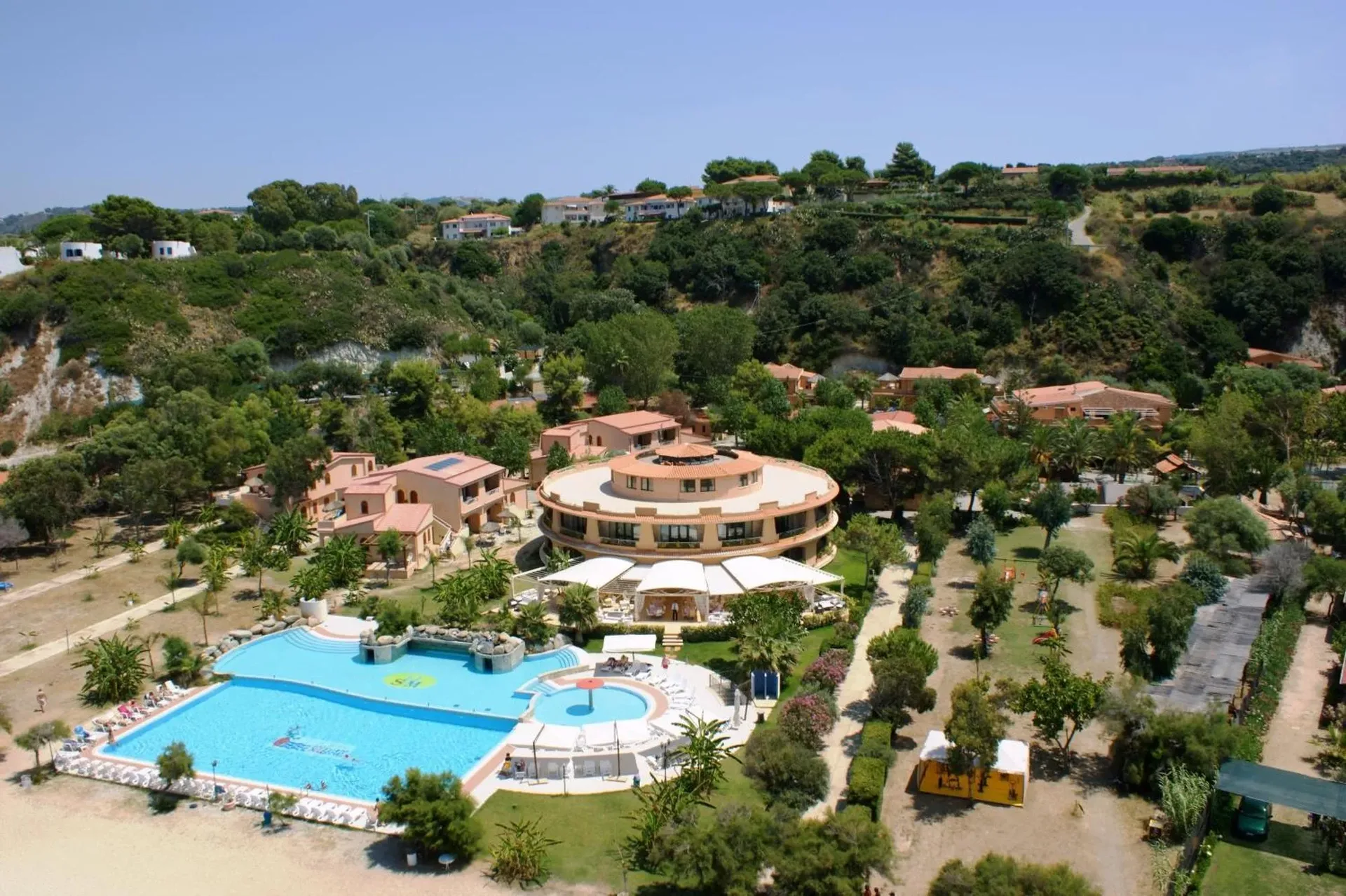 Veduta aerea del resort immerso nel verde con piscina e edificio circolare
