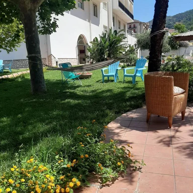 Giardino dell'hotel con amaca, poltrone in vimini, sedie azzurre e fiori gialli
