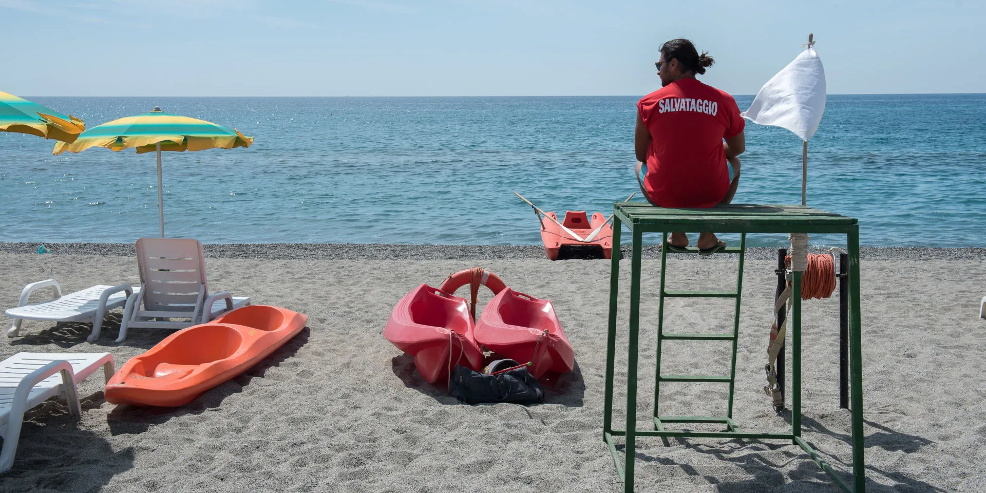 Bagnino di salvataggio sulla spiaggia con pattini e ombrelloni colorati