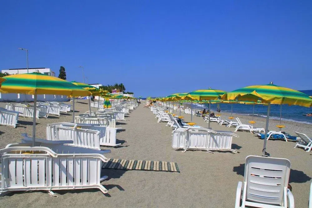 Lettini e ombrelloni gialli e verdi allineati sulla spiaggia di sabbia