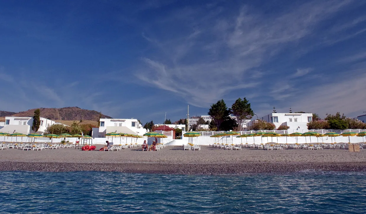 Spiaggia dell'hotel vista dal mare con case bianche e ombrelloni