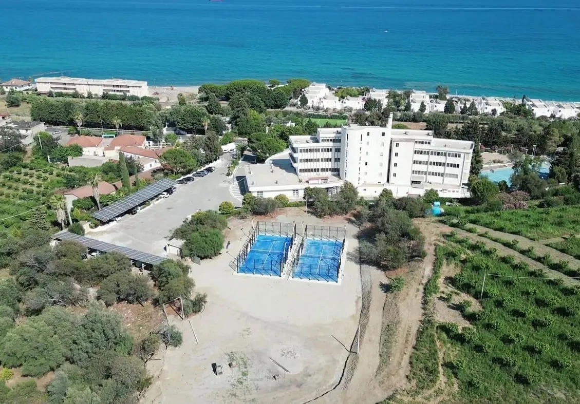 Veduta aerea dell'hotel con campi sportivi e pannelli solari vicino al mare