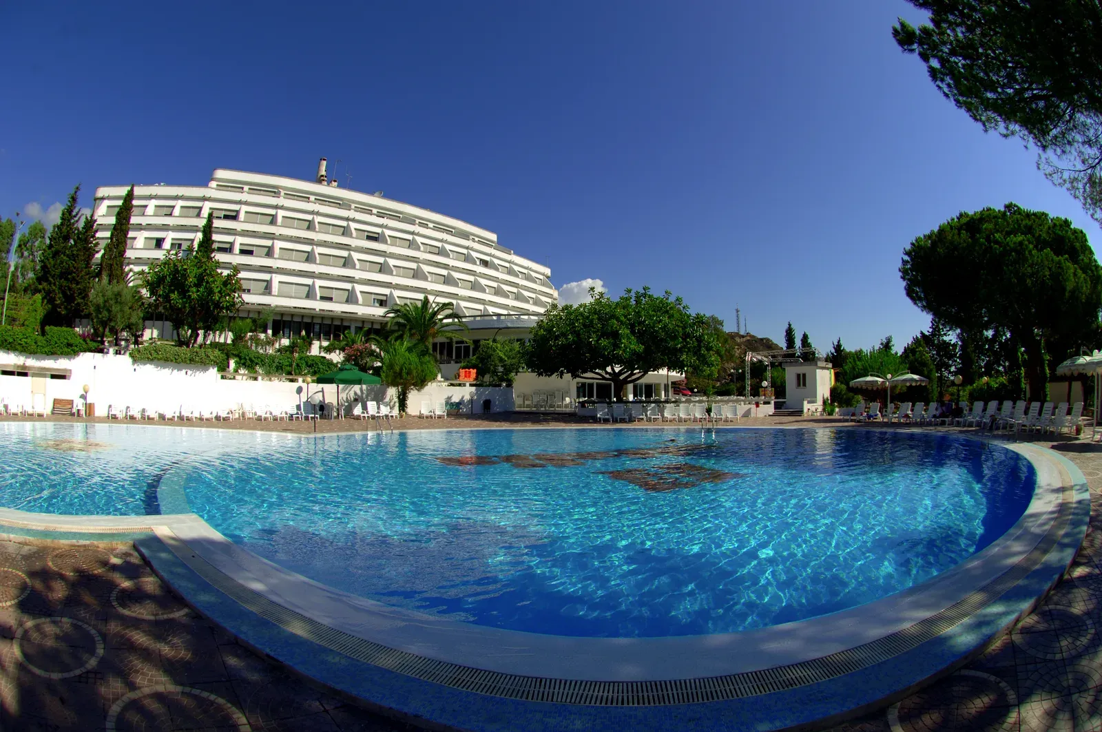 Ampia piscina con vista sull'edificio curvilineo dell'hotel e alberi