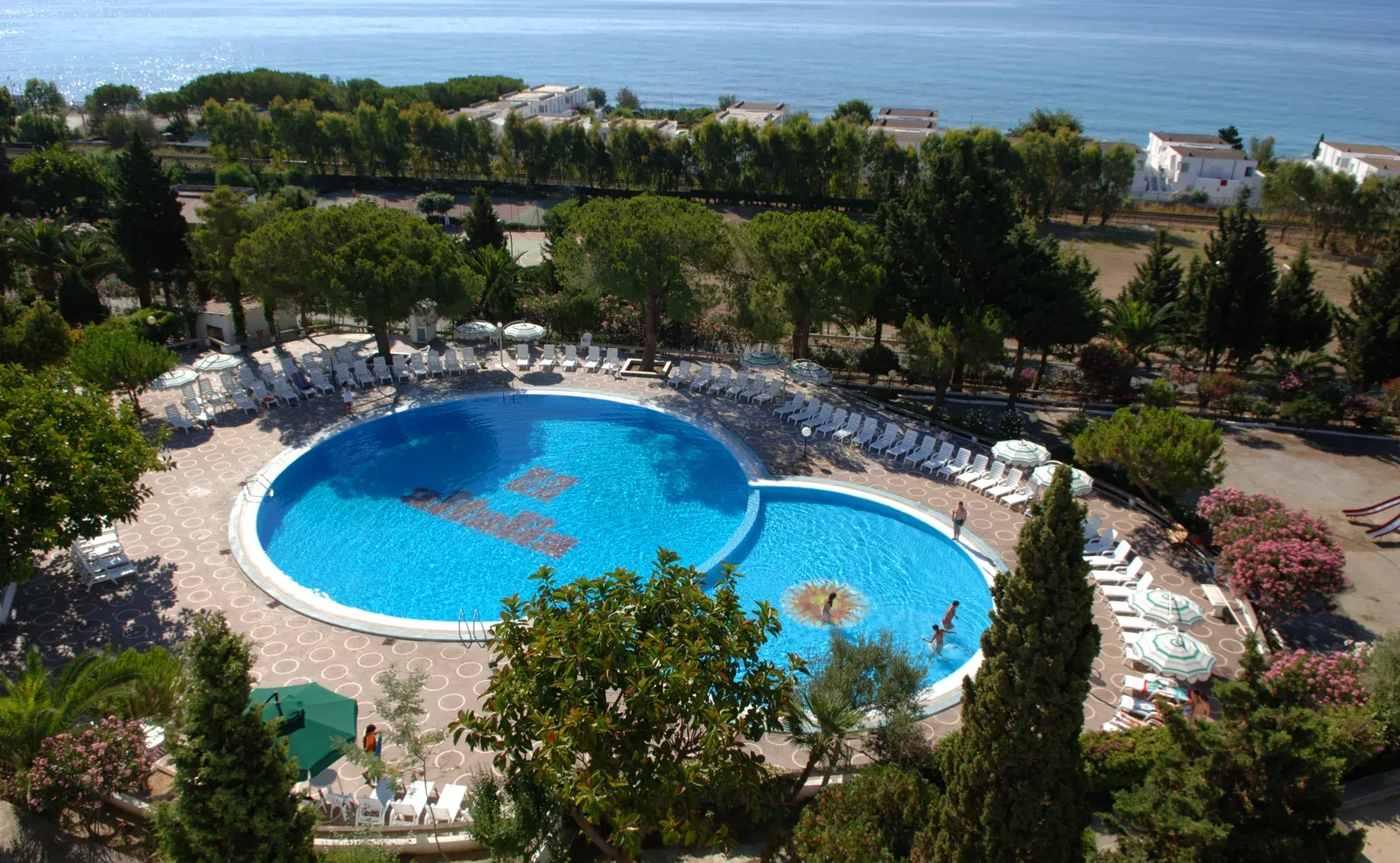 Piscina a doppia forma circondata da giardino con vista sul mare