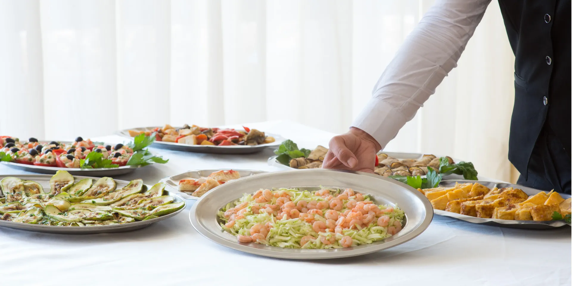 Buffet con piatti di antipasti freddi e cameriere che serve