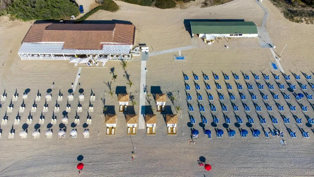 Vista aerea della spiaggia con ombrelloni, lettini blu e chiosco bar