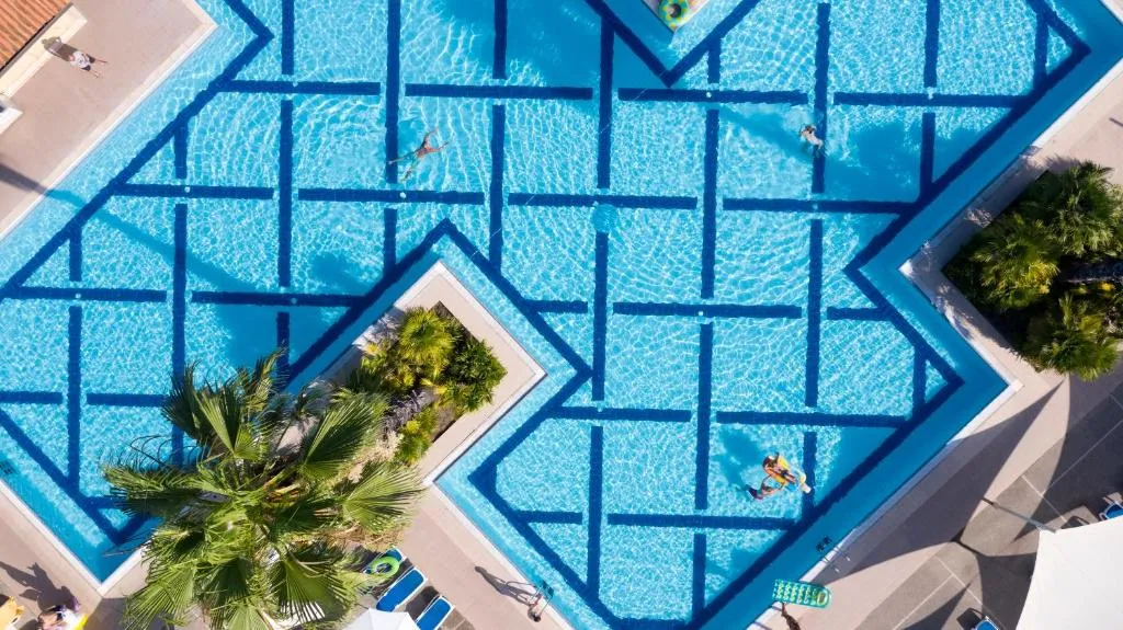 Vista aerea della piscina con motivi geometrici azzurri e palme