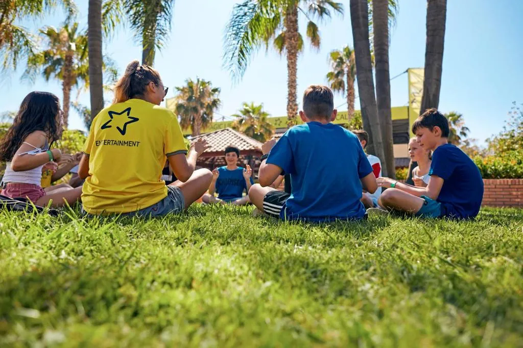 Animatori e bambini seduti sul prato durante attività di intrattenimento all'aperto