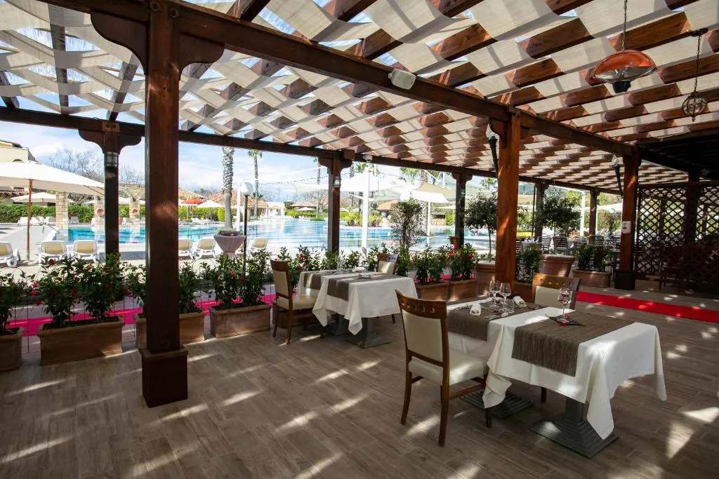 Ristorante con pergolato in legno e tavoli eleganti affacciati sulla piscina