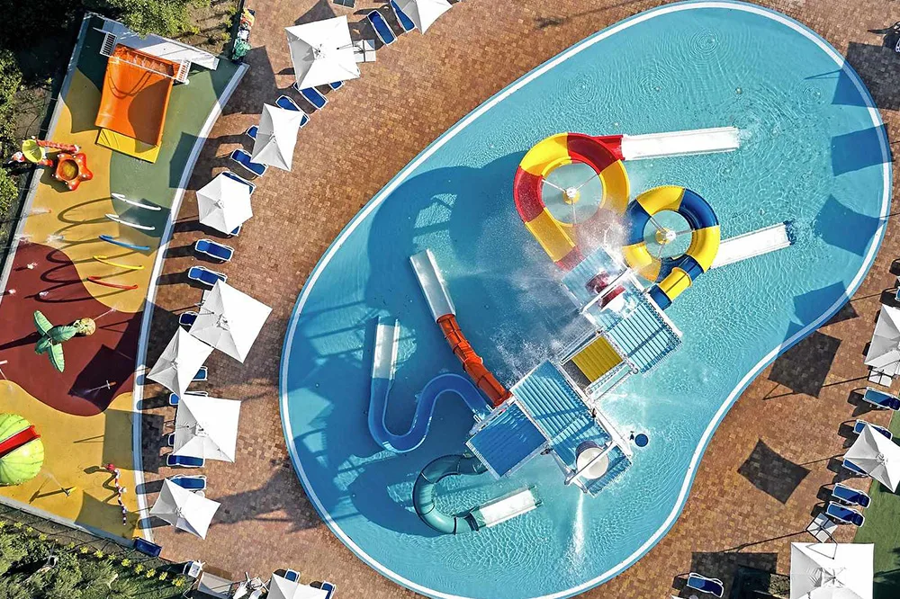 Parco acquatico per bambini con scivoli colorati e giochi d'acqua visto dall'alto