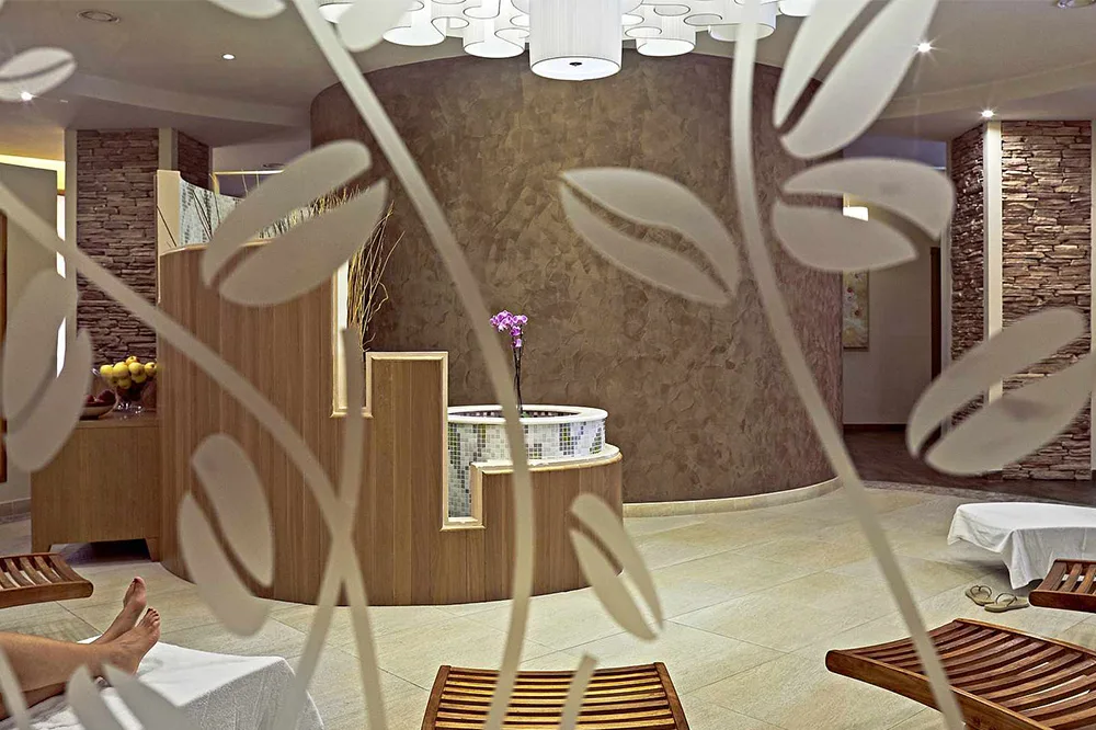 Interno della spa con lettini in legno, vasca idromassaggio e atmosfera rilassante