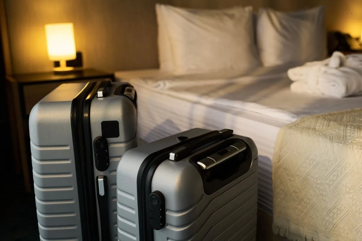 Due valigie grigie accanto a un letto con accappatoi in una camera d'albergo
