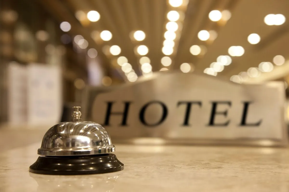 Campanello da reception su bancone con insegna Hotel e luci sfocate sullo sfondo