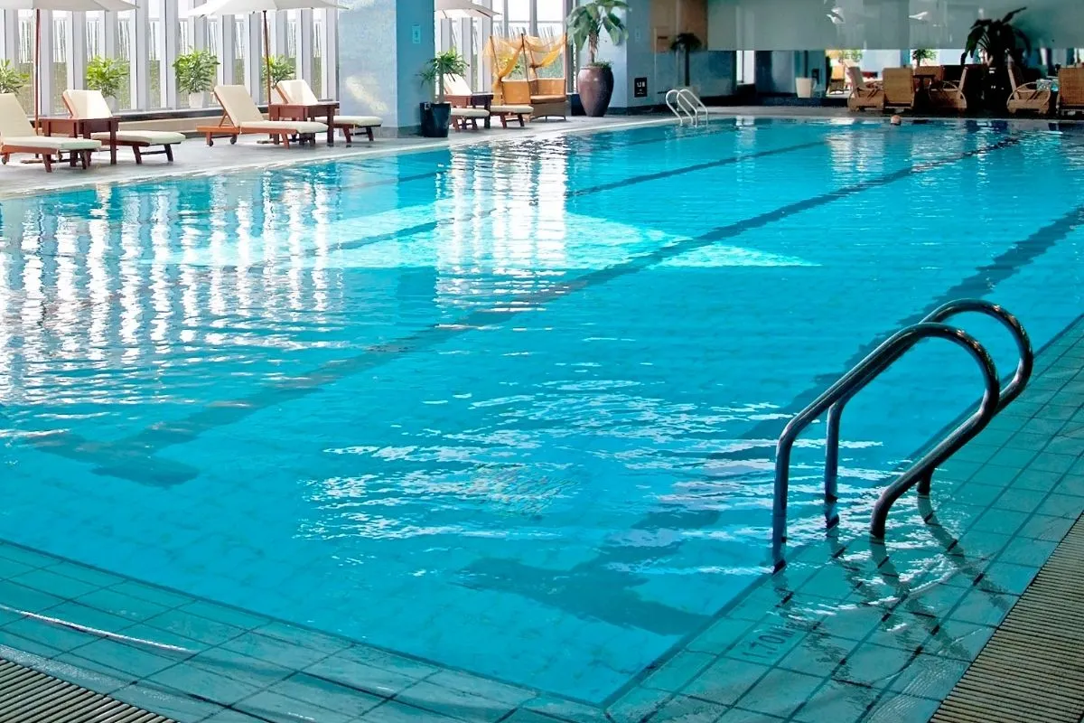 Piscina coperta interna con corsie, lettini in legno e ampie vetrate