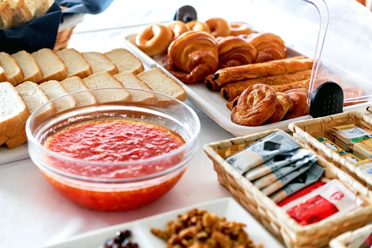 Buffet di colazione con pane, cornetti, marmellata e confezioni varie