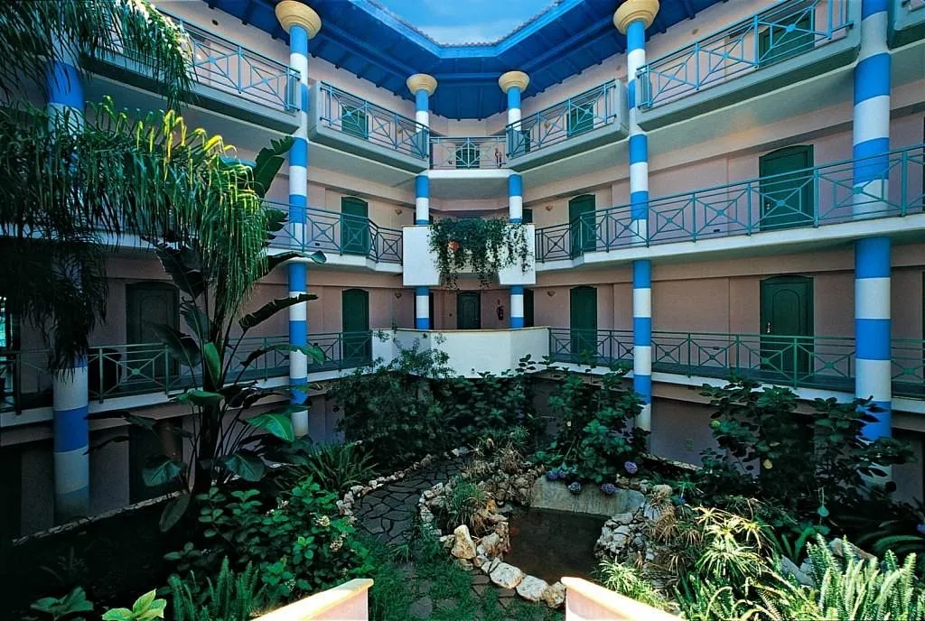 Cortile interno dell'hotel con colonne blu e bianche e giardino centrale