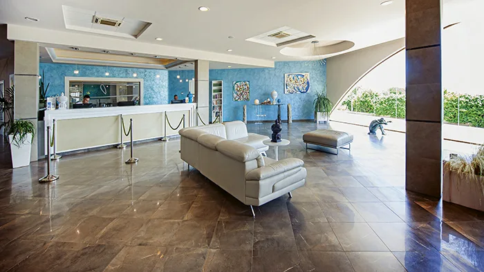 Hall dell'hotel con reception, pareti azzurre, divano e pavimento lucido