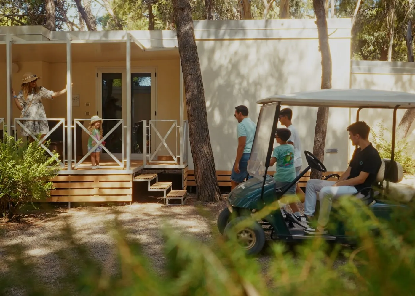 Famiglia con golf cart davanti a una casetta mobile nella pineta