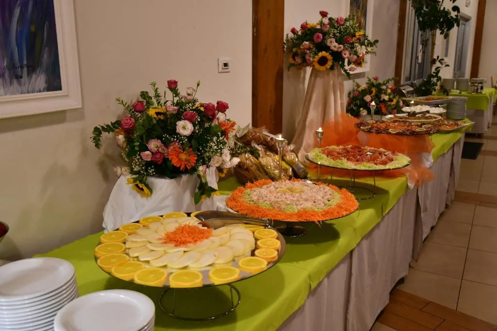 Buffet con piatti di salumi, verdure e composizioni floreali