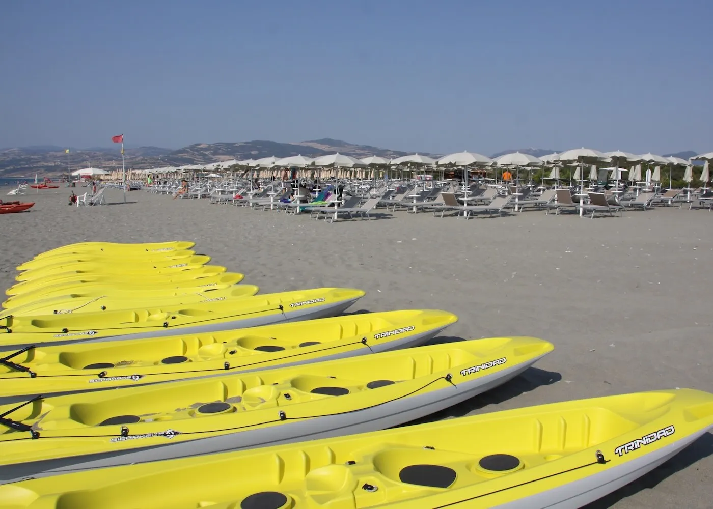Canoe gialle allineate sulla spiaggia con ombrelloni sullo sfondo